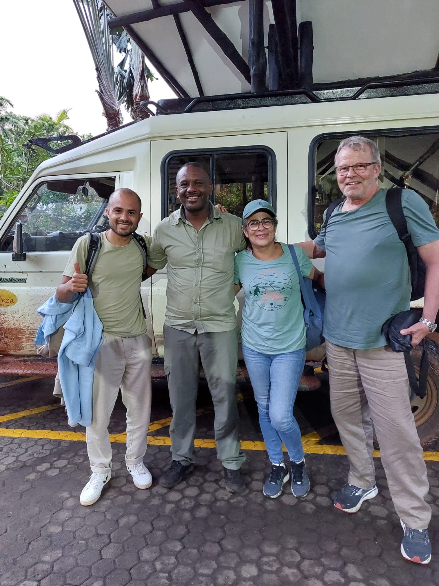 Khweza guide with guests beside a pop-top safari vehicle